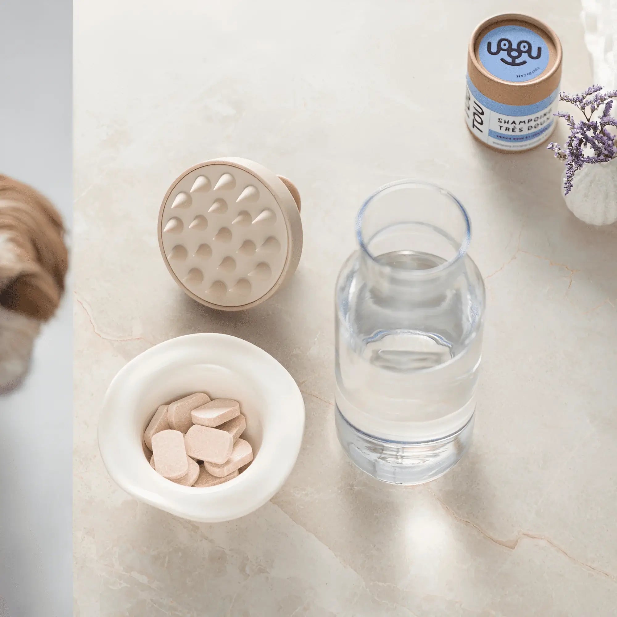 Pastilles de shampoing biodégradables pour chien avec argile rose et huile de géranium, bouteille d'eau et accessoire de lavage.